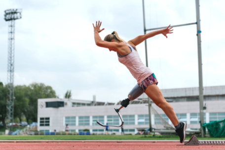 Female Athlete with Prosthetic Leg Running on Track Exercise and Breast Support
