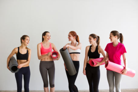 Group of five women in activewear holding yoga mats breast health
