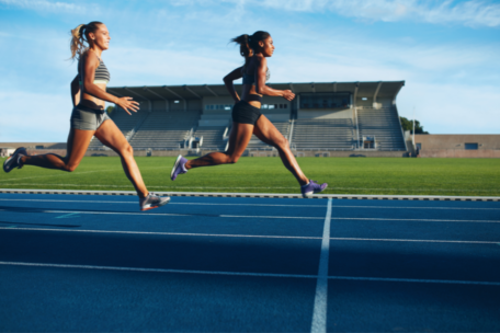 Two Female Athletes Running Across Finish Line Menstrual Cycle Management Strategies